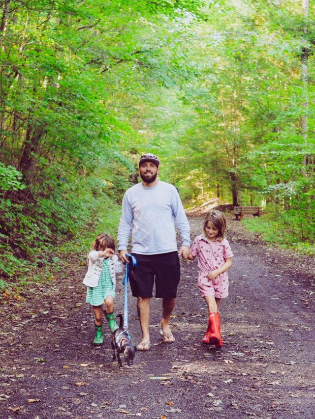 parent walking with two children on trail in woods
