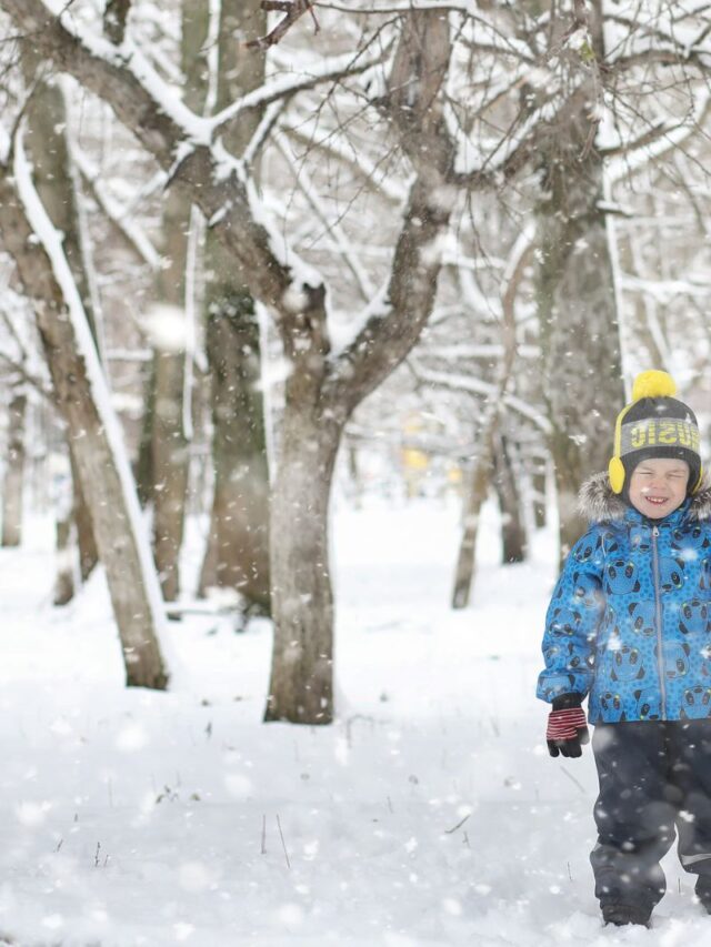 child standing outside while it's snowing